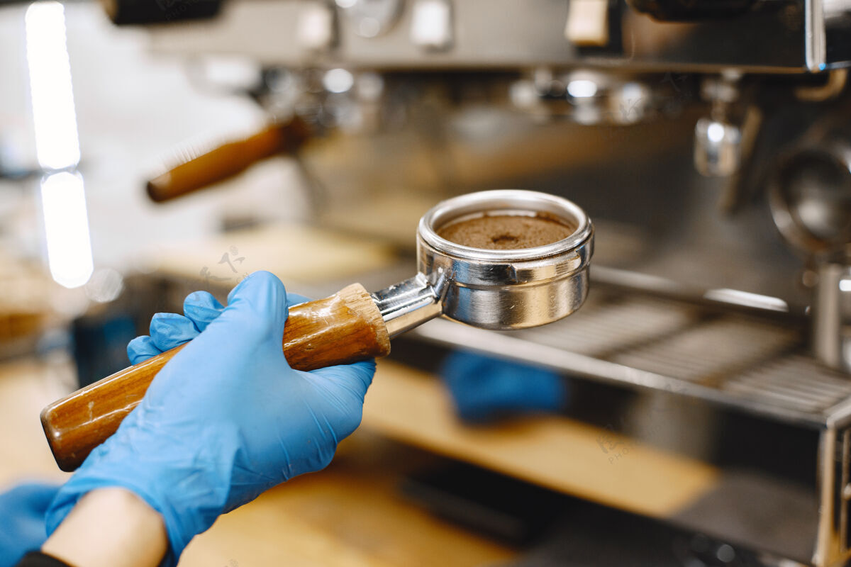 制造商咖啡师准备咖啡咖啡架里的咖啡戴着手套的手捣碎机设备黑色