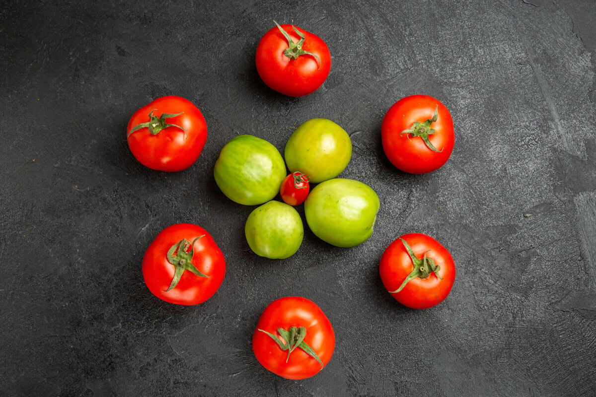 蔬菜顶视图红色和绿色西红柿围绕着一个樱桃西红柿在黑暗的地面与复制空间番茄素食者食品