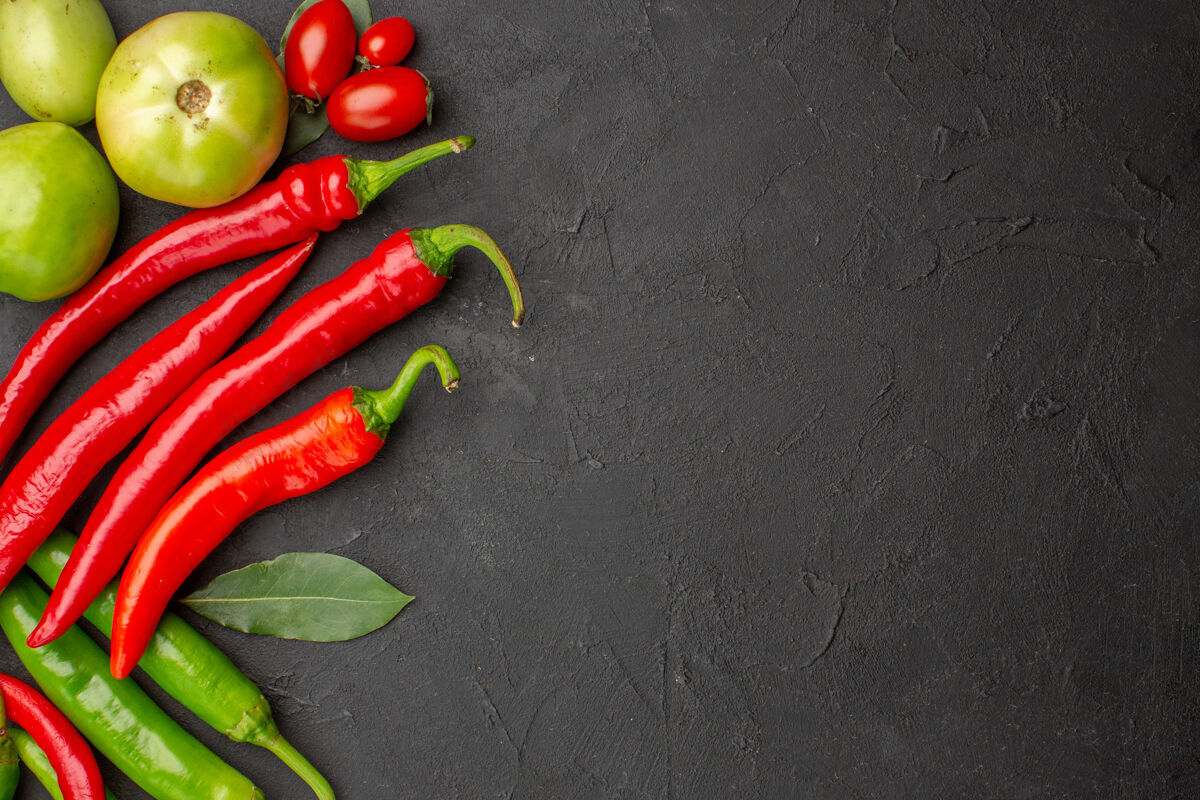 健康顶视图红色和绿色的辣椒和西红柿叶在左侧的黑土地与自由空间蔬菜素食地面