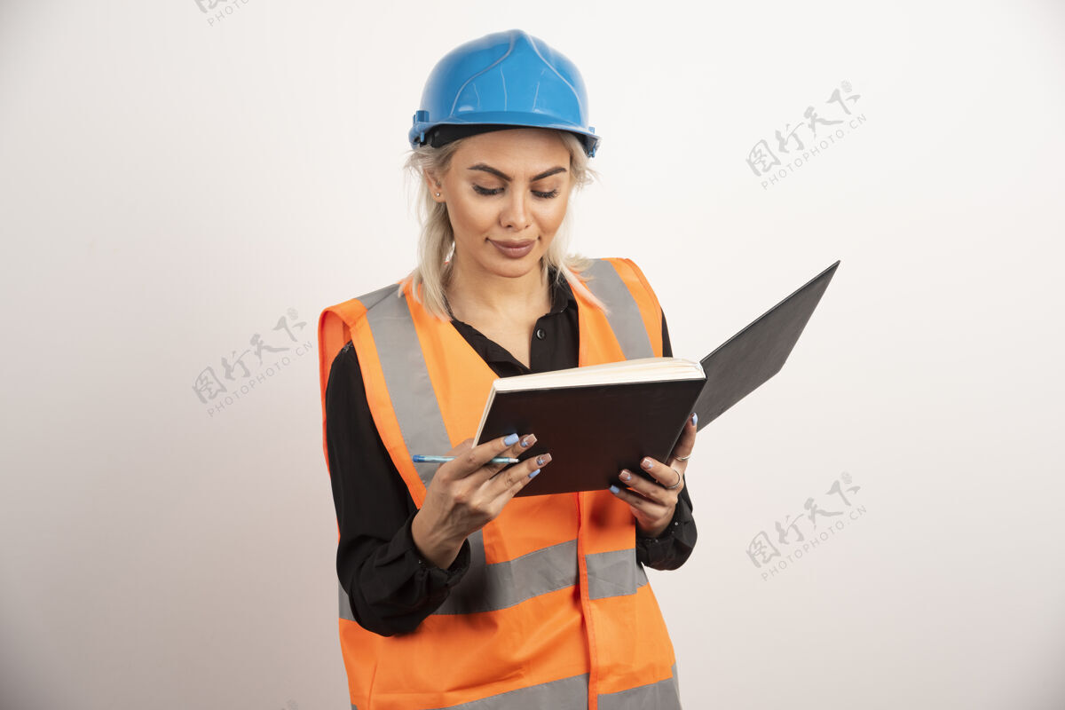 笔记本美丽的建筑工人在白色背景上检查笔记高质量的照片人工人微笑