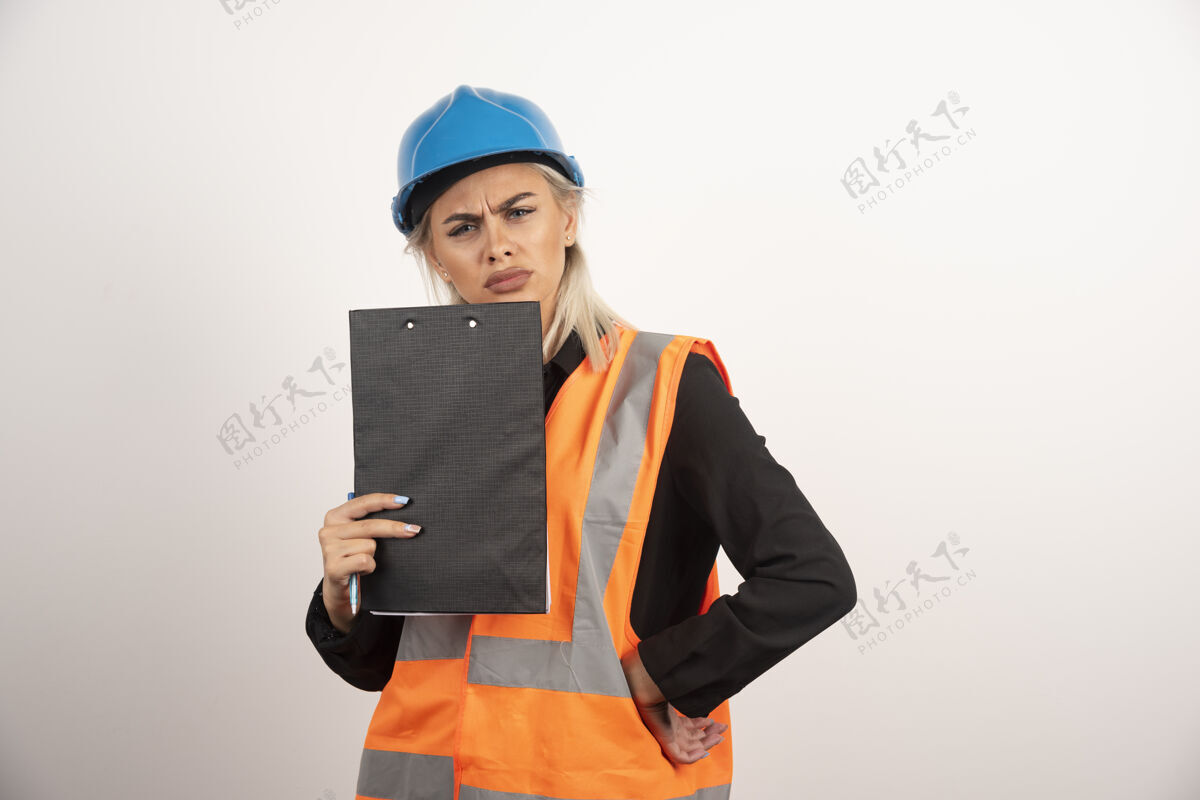 安全帽带着剪贴板的女工摆出不高兴的样子高质量的照片工人背心成人