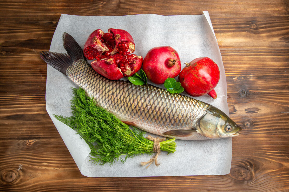 海洋棕色木质书桌上的石榴鲜鱼俯瞰图美食肉食物