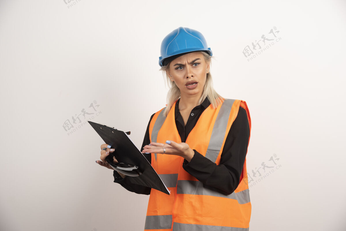 护目镜不满的妇女建设者指着剪贴板高品质的照片铅笔头盔女士