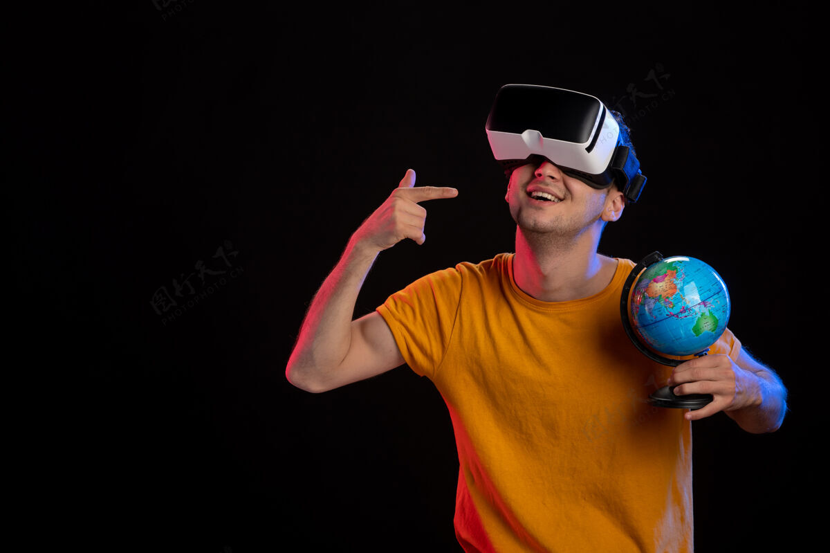 虚拟在黑暗的表面上玩虚拟现实拿着地球仪的年轻男性年轻男性运动肖像