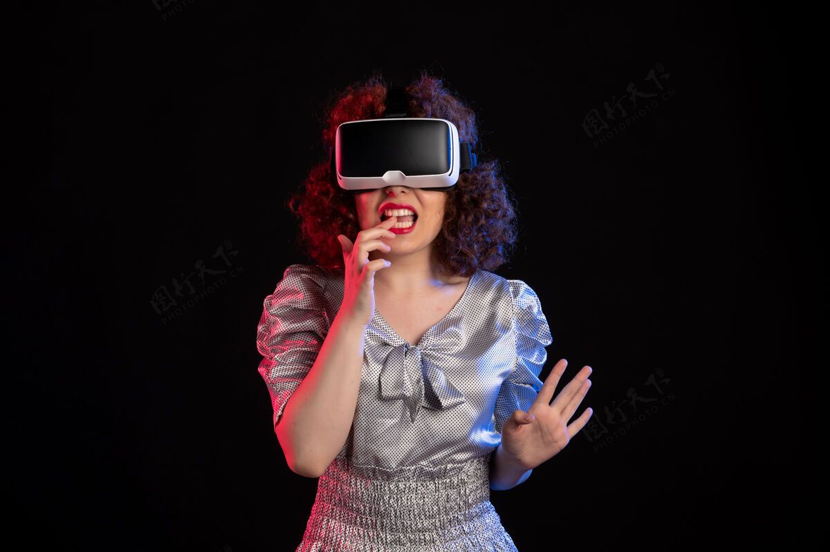 虚拟年轻女性戴着虚拟现实耳机在黑暗的表面游戏女性年轻女性