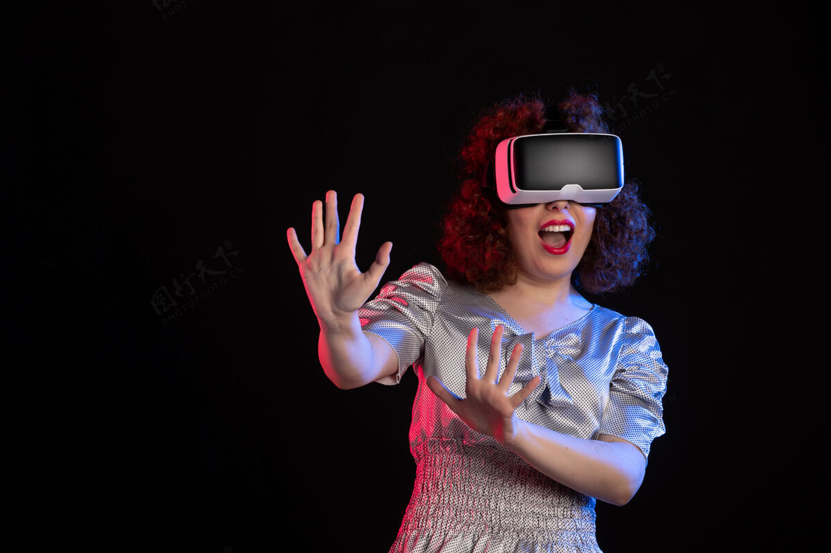 女人美丽的女性戴着虚拟现实耳机在黑暗的表面虚拟姿势现实
