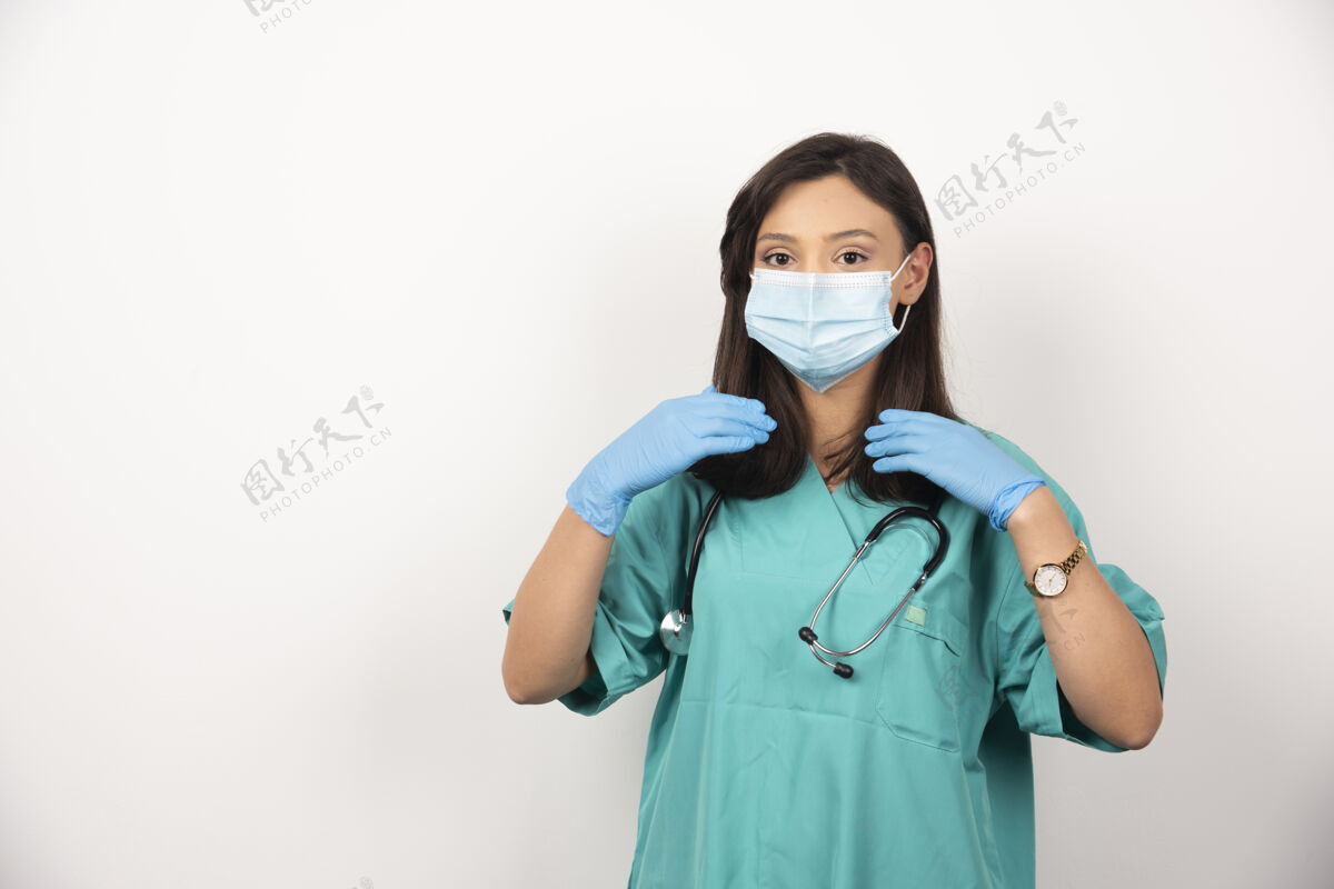 工作戴口罩的女医生在白色背景上检查头发高质量照片听诊器医疗女性