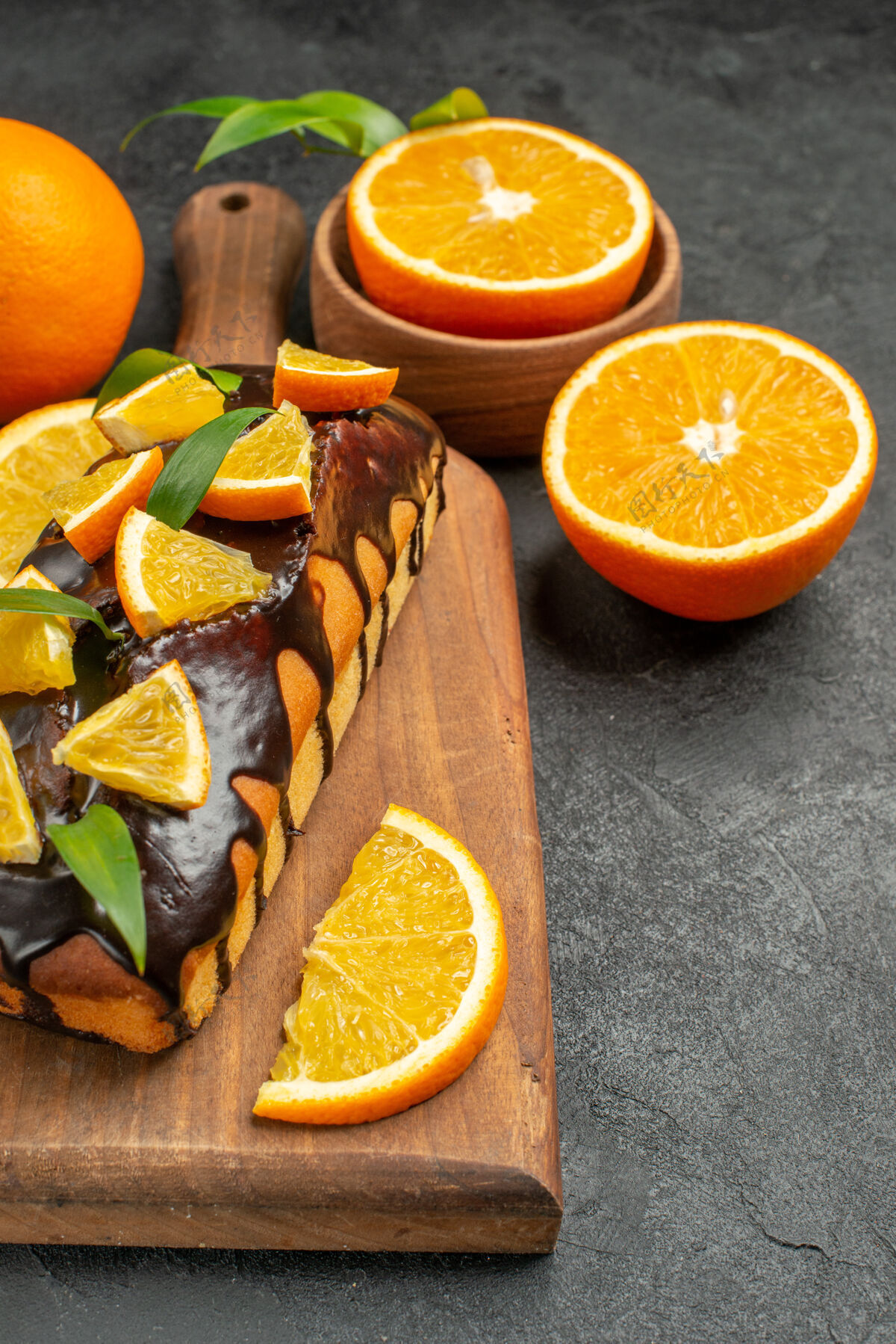 健康整个美味蛋糕和切柠檬的垂直视图放在黑色桌子的砧板上橙子柑橘柠檬