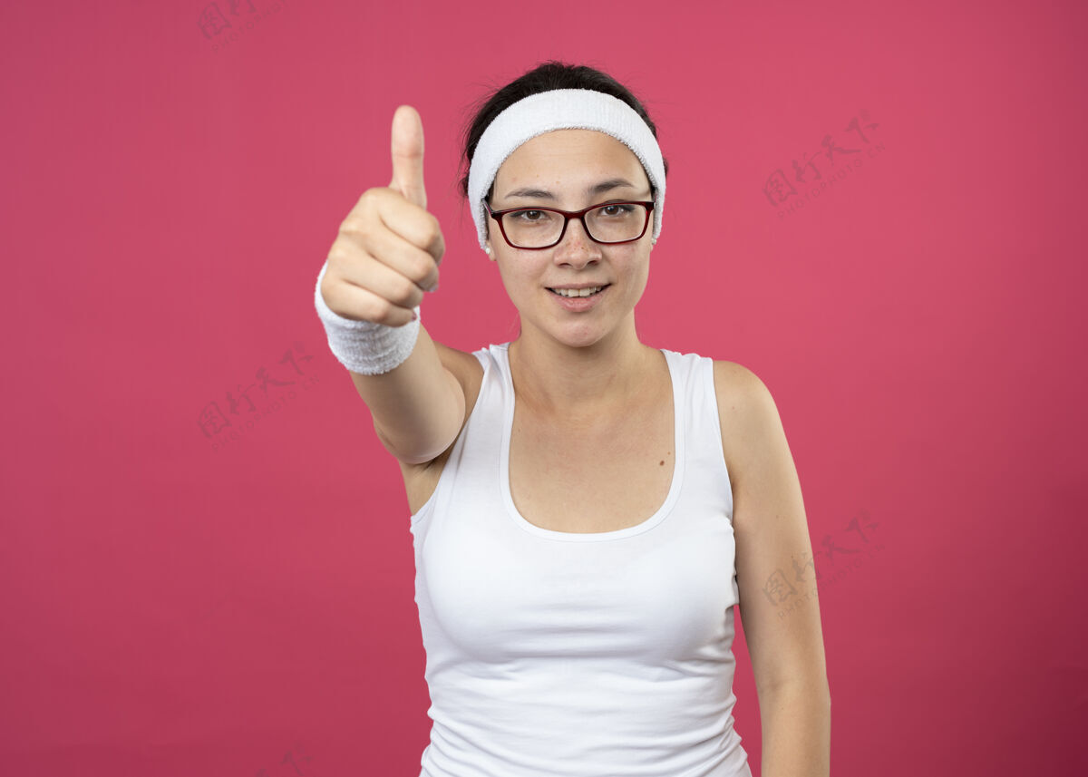 年轻戴着眼镜 戴着头带 面带微笑的年轻运动女孩运动拇指头带