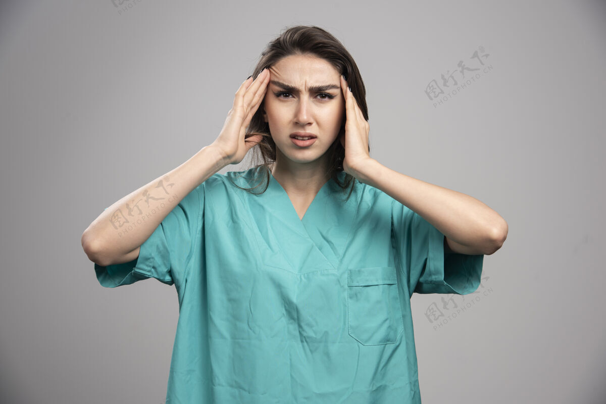 年轻女医生头痛的灰色背景高质量的照片健康工作肖像