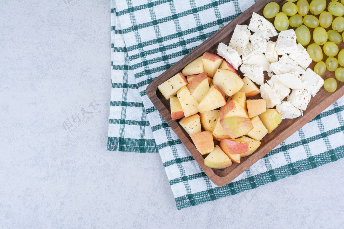 美食一块装满白奶酪和水果切片的木板切割食物产品