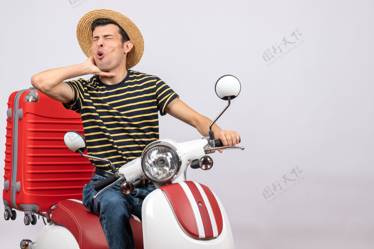 轻便摩托车前视图：年轻人戴着草帽坐在轻便摩托车上忍着喉咙痛年轻人摩托车喉咙