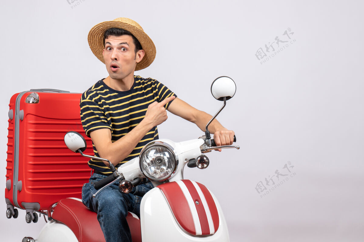 车辆前视图好奇的年轻人与草帽轻便摩托车指向白色背景轻便摩托车指向白人