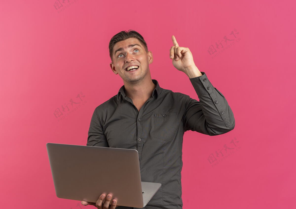 年轻年轻的金发帅哥拿着笔记本电脑 抬头看了看惊喜粉红色男人