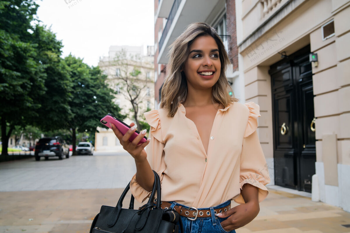 通讯年轻女子在街上户外散步时使用手机的画像使用发送电话