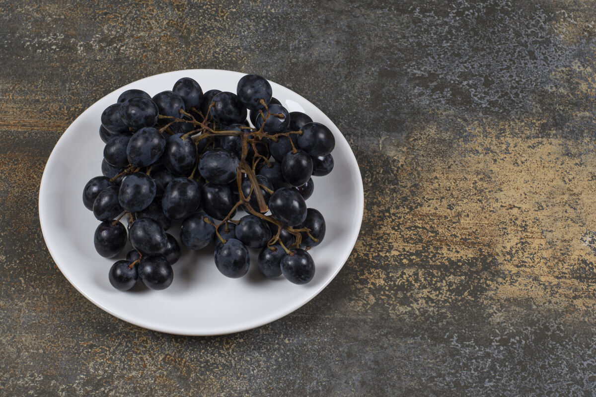 新鲜白色盘子上的一簇黑葡萄葡萄自然浆果