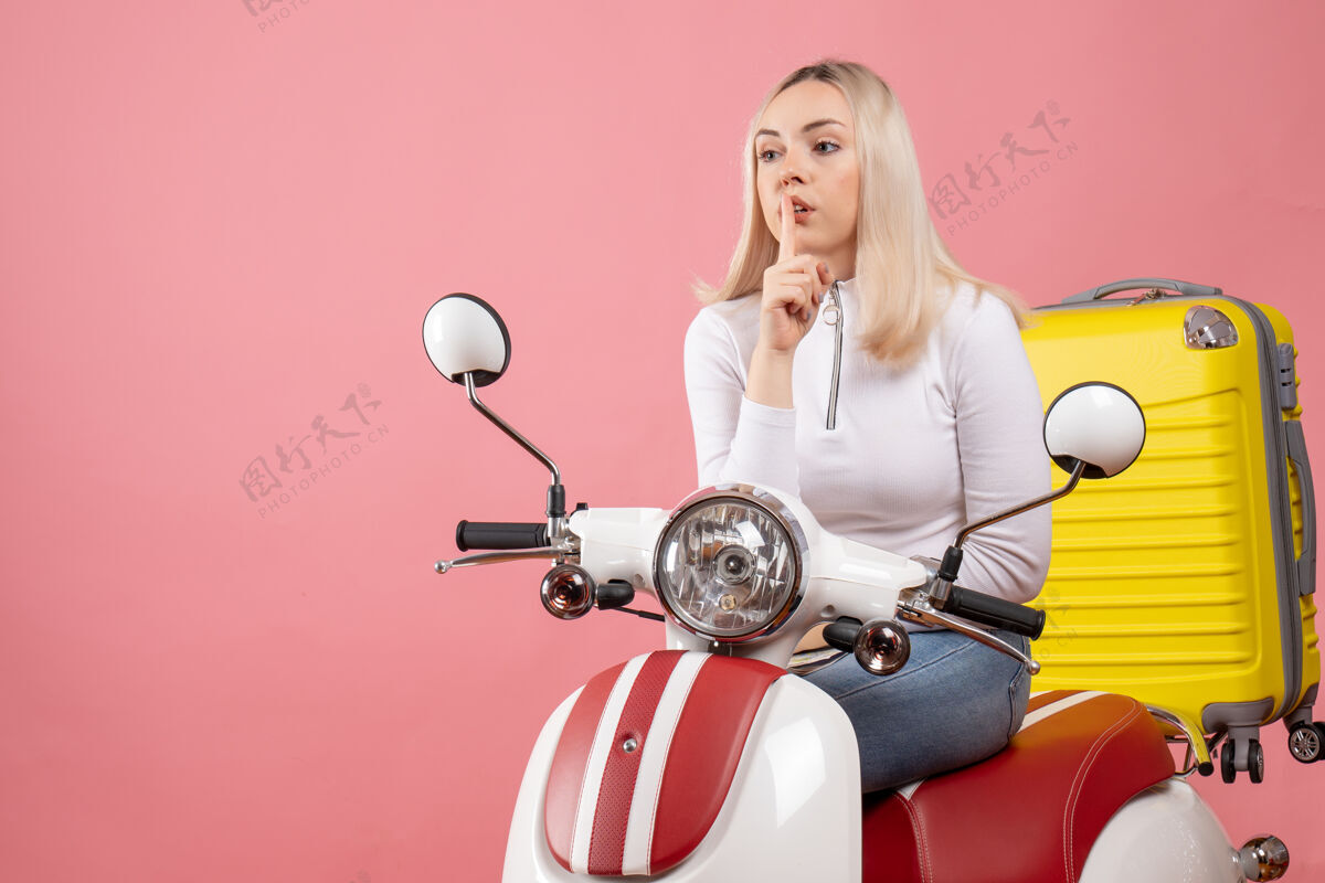 年轻女士前视图：骑着轻便摩托车的年轻女士示意安静成人轻便摩托车车辆