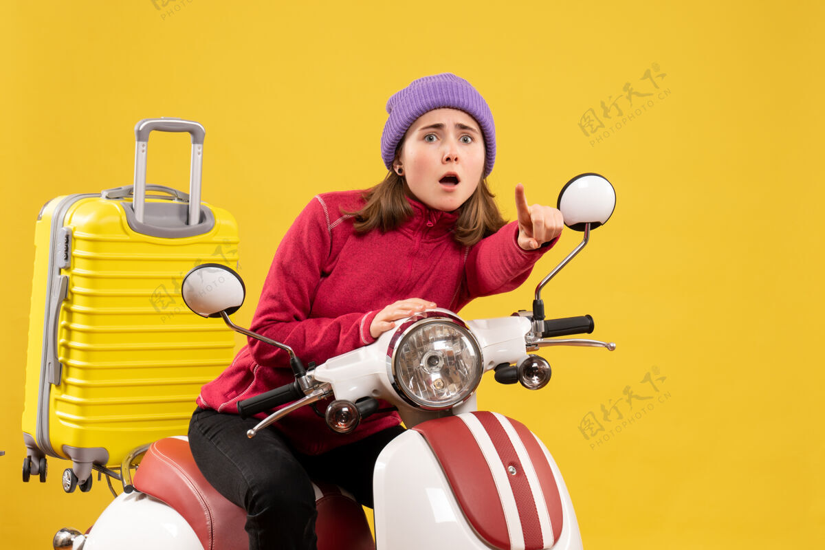 年轻女孩前视图骑着轻便摩托车的年轻女孩指着运输机车辆摩托车
