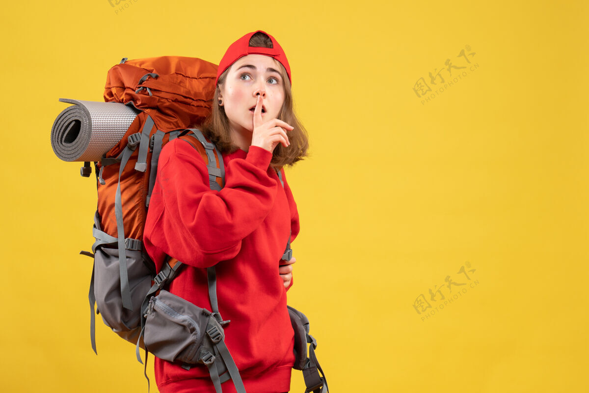 正面正面图：背着背包的年轻女旅行者在做安静的标志快乐制造成人