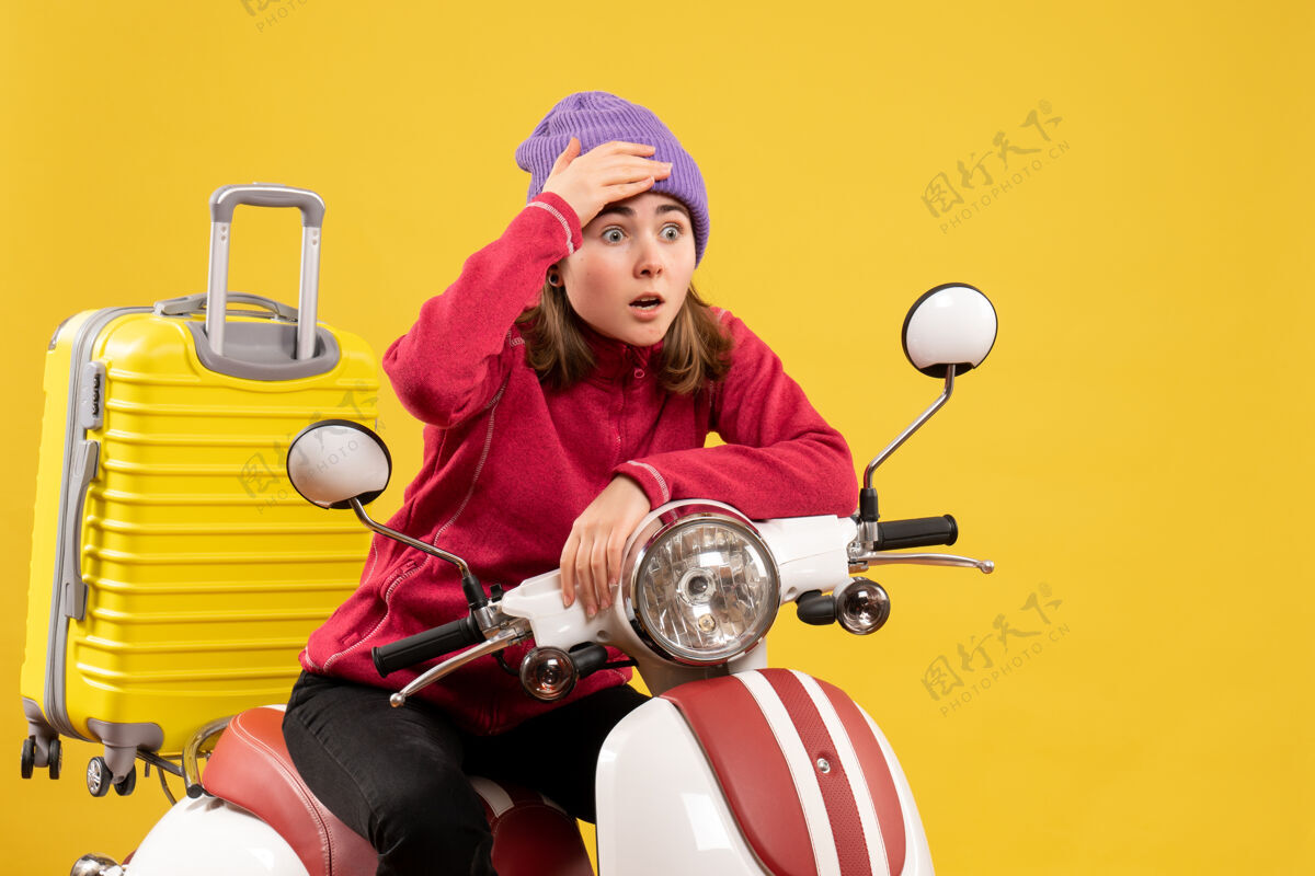 保持前视图坐在轻便摩托车上的年轻女孩抱着头看着什么传送带头部摩托车
