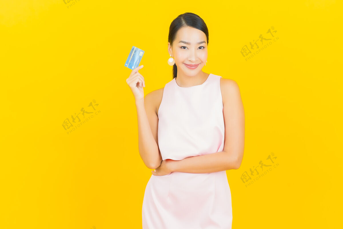 亚洲肖像美丽的亚洲年轻女子微笑信用卡上的黄色显示持有女性