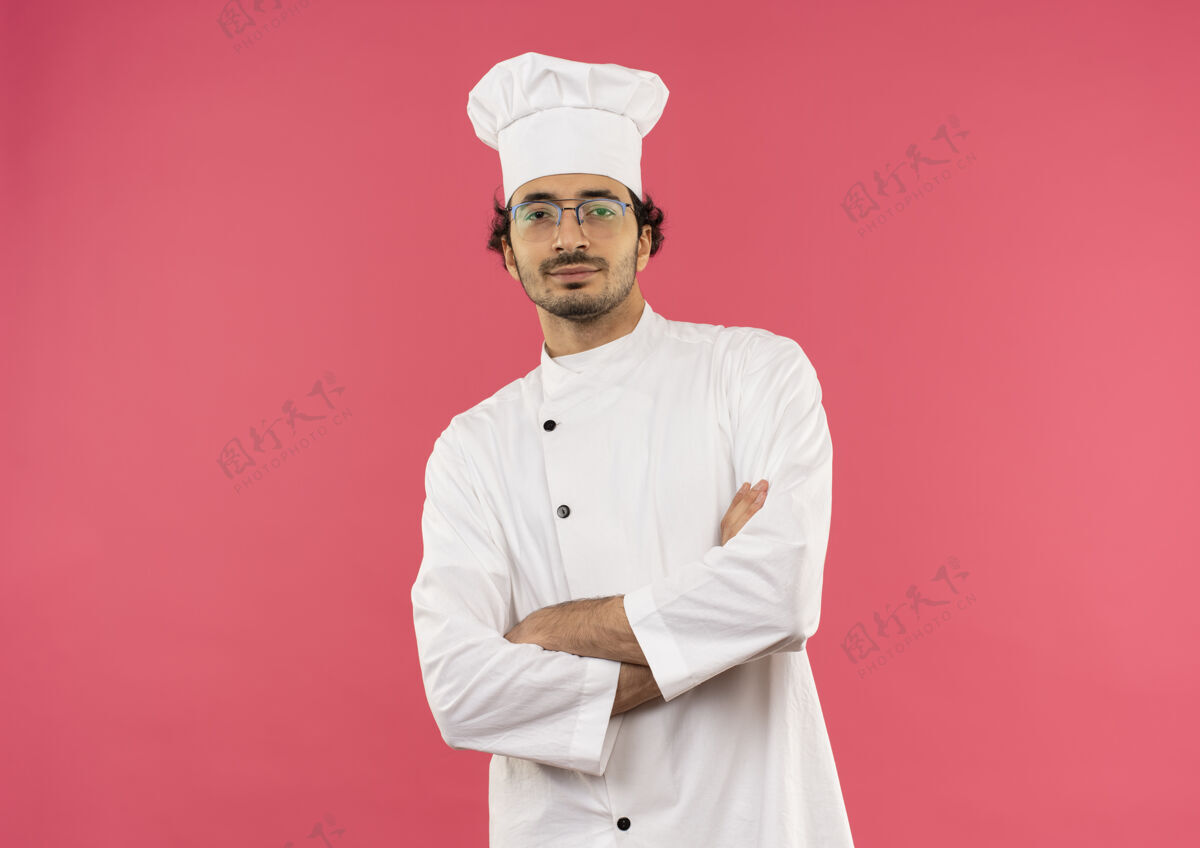 手自信的年轻男厨师穿着厨师制服和眼镜双手交叉制服烹饪年轻