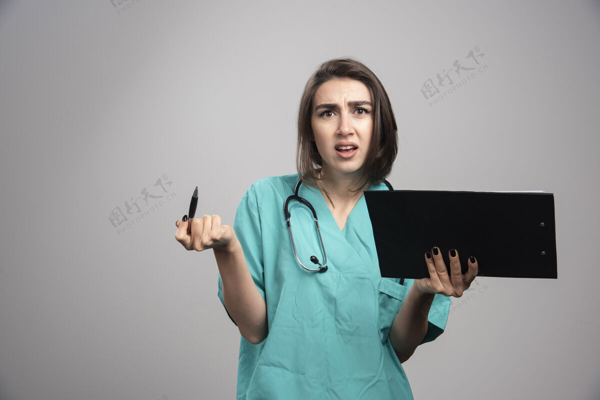 医院疲惫的医生拿着剪贴板在灰色背景上高质量的照片医生肖像工作