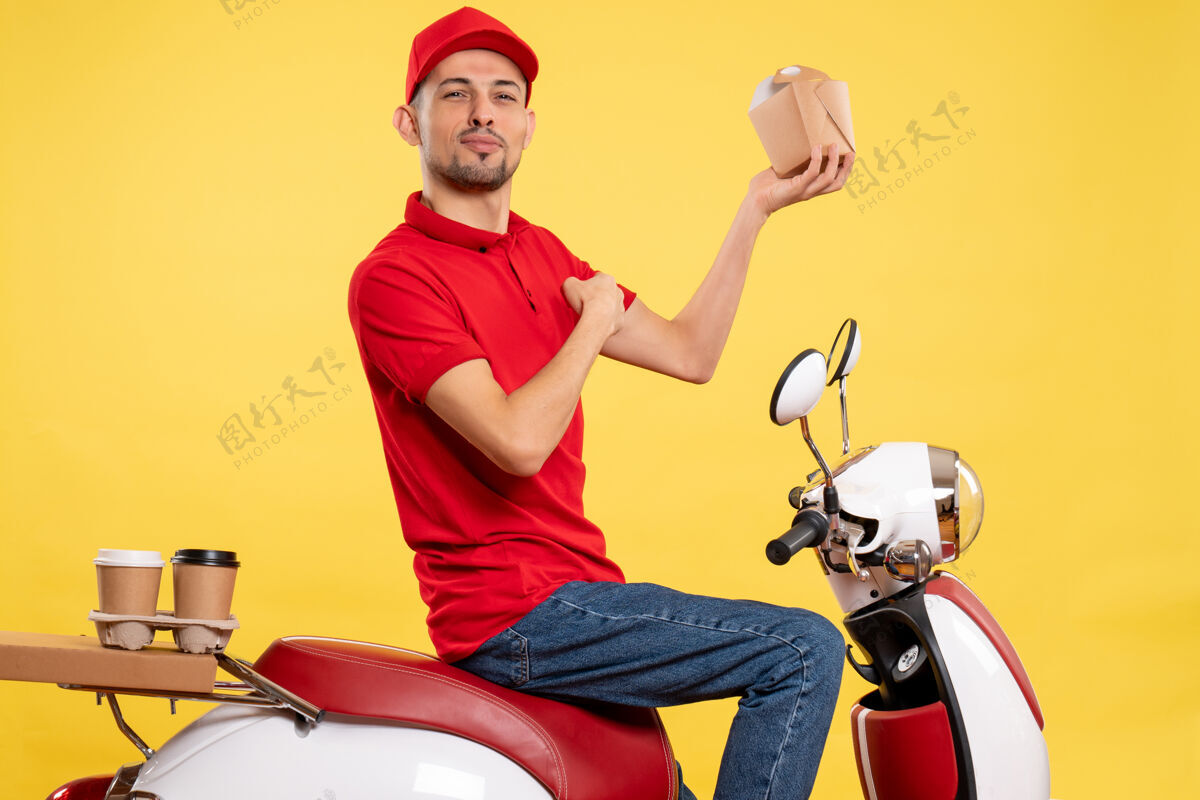 红色正面图身穿红色制服的年轻男性快递员 黄色背景上有送货食品年轻男性快递员正面景观
