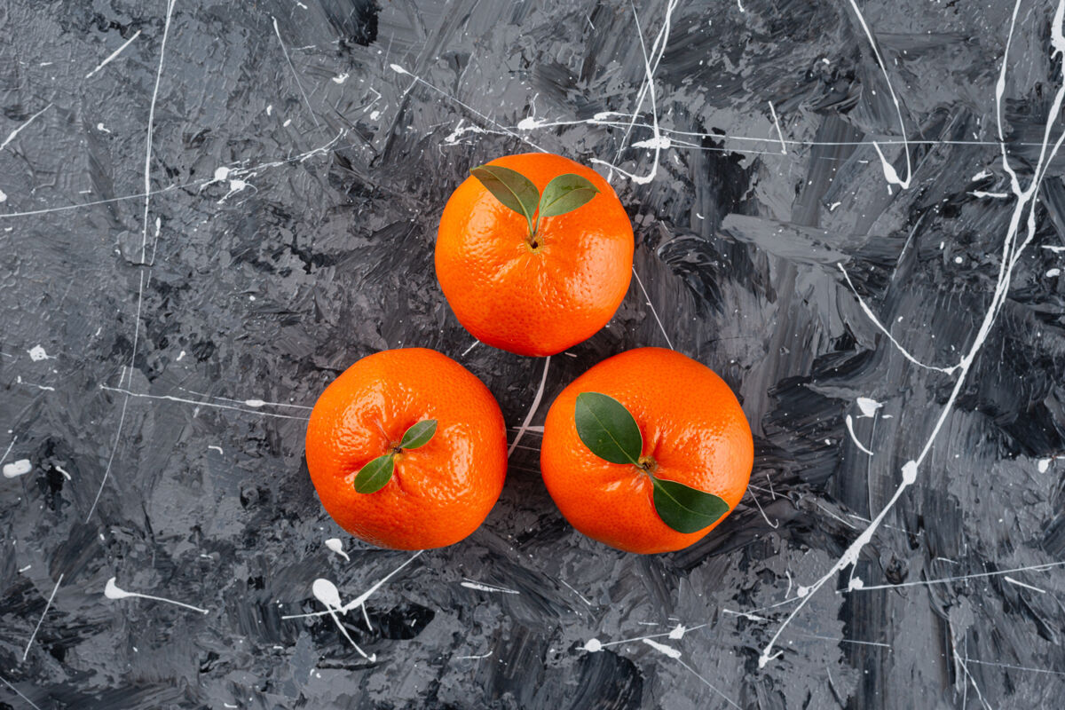 多汁三个多汁的橘子 大理石表面有叶子成熟柑橘健康