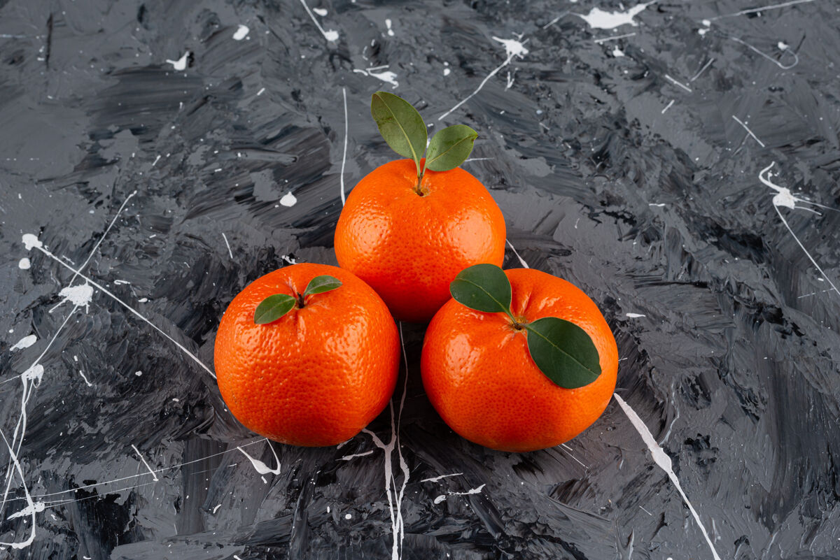 美味三个多汁的橘子 大理石表面有叶子自然热带鲜亮