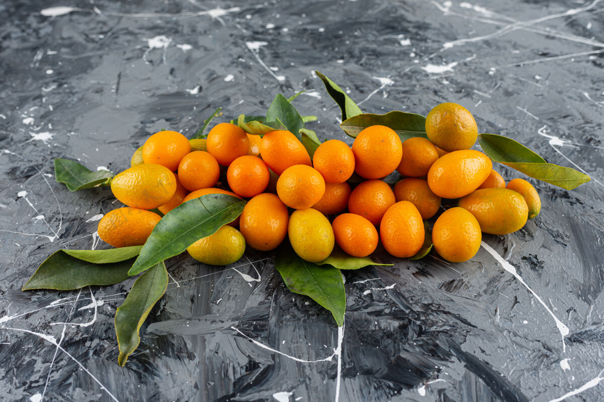 金橘一堆成熟的金橘 大理石表面有绿叶全熟美味有机