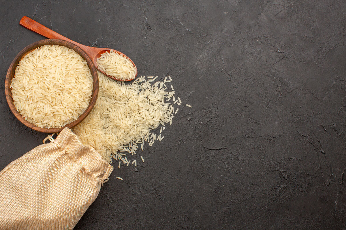 烹饪在灰色表面的棕色盘子里的生大米的顶视图生的热带大米