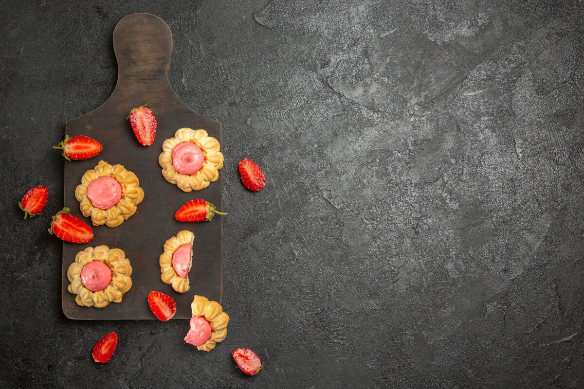 爱灰色表面上草莓奶油小甜饼的俯视图玩具饼干草莓