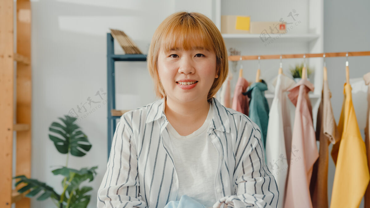 信心一幅年轻的亚洲女时装设计师的画像 她微笑着 双臂交叉 看着前方 在家里的服装店工作忙碌票房股票