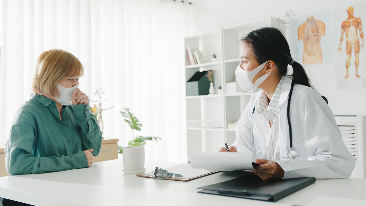 剪贴板年轻的亚洲女医生戴着防护面罩 用剪贴板和医院办公室的女病人讨论结果或症状医疗流感女性