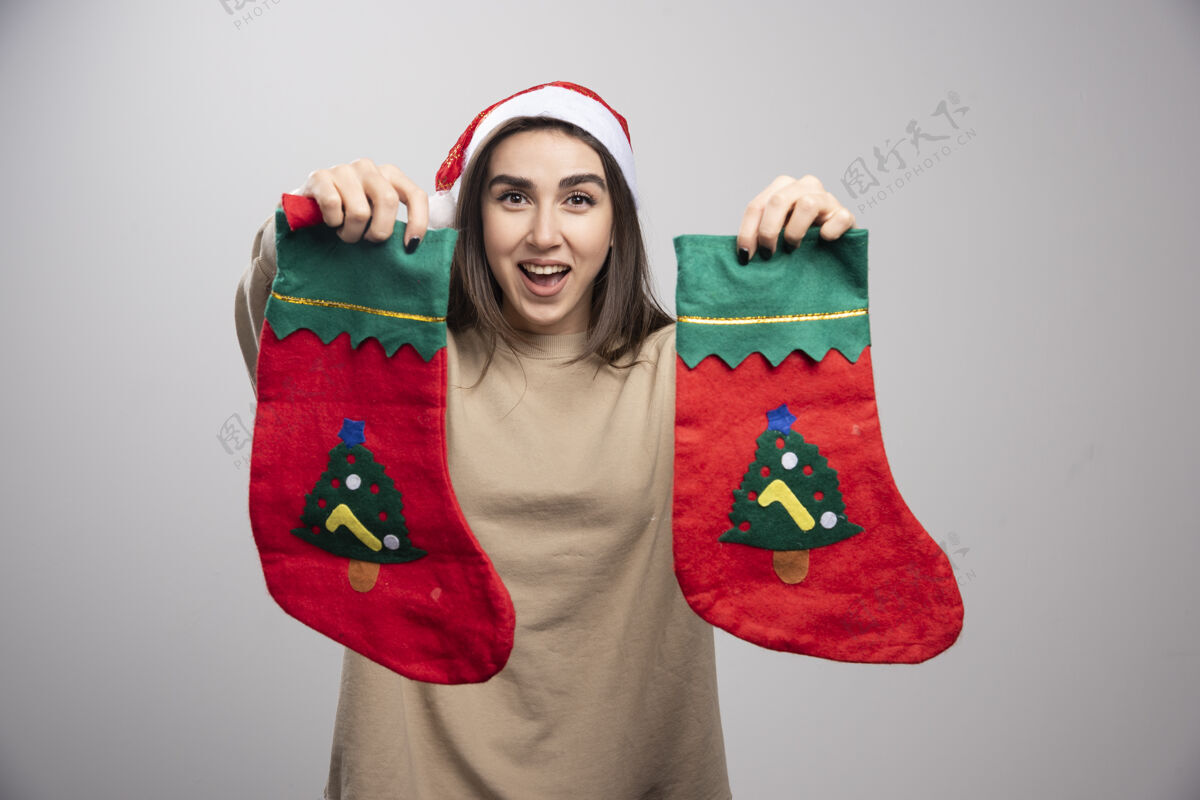人戴着圣诞老人帽子的小女孩在展示两只圣诞袜子张开惊人宽