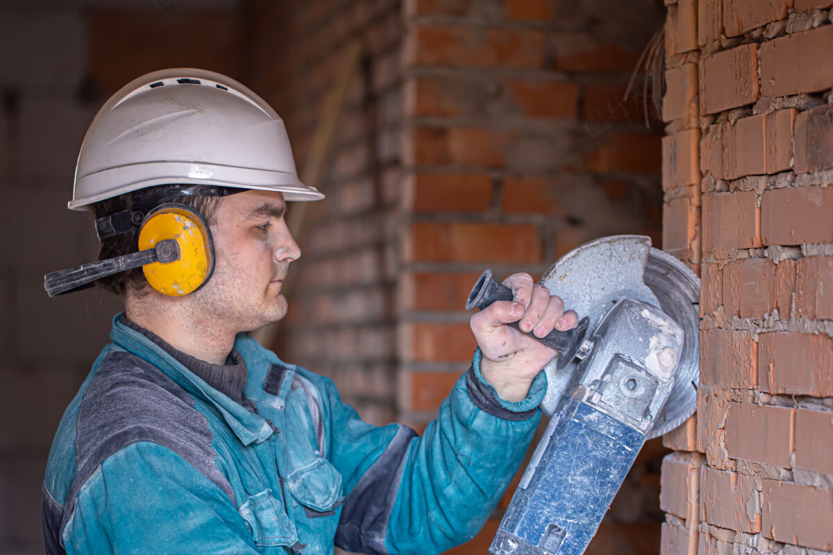 角钢一个建筑工人戴着安全帽在工作场所用切割工具工作的特写镜头杂工机械工作服