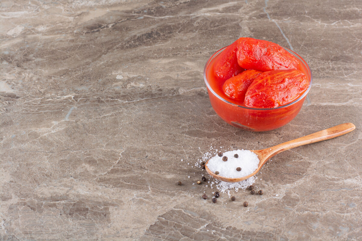 泡菜石桌上放着一碗腌番茄和盐成熟盐零食