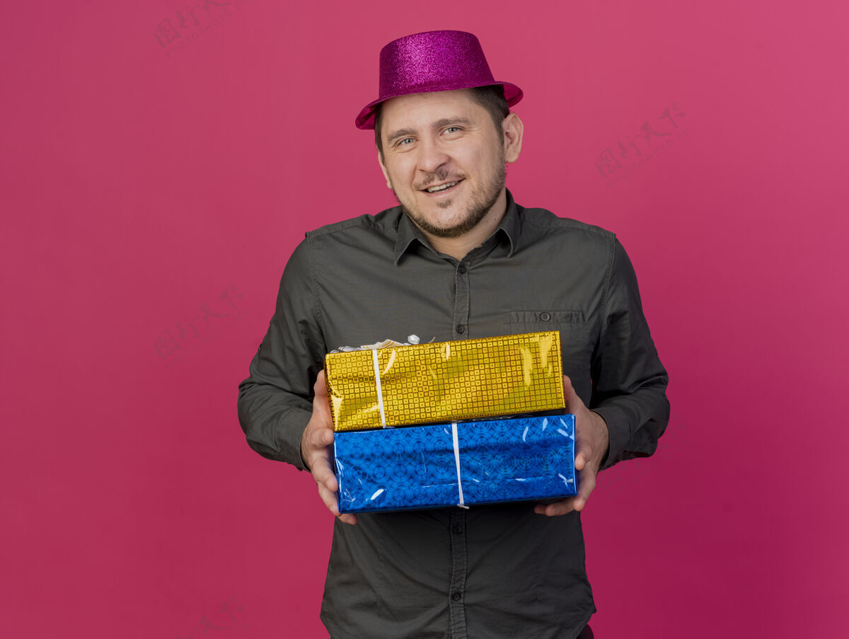 帽子一个戴着粉色帽子 拿着礼品盒 孤零零地站在粉色地板上的年轻人盒子拿着礼物