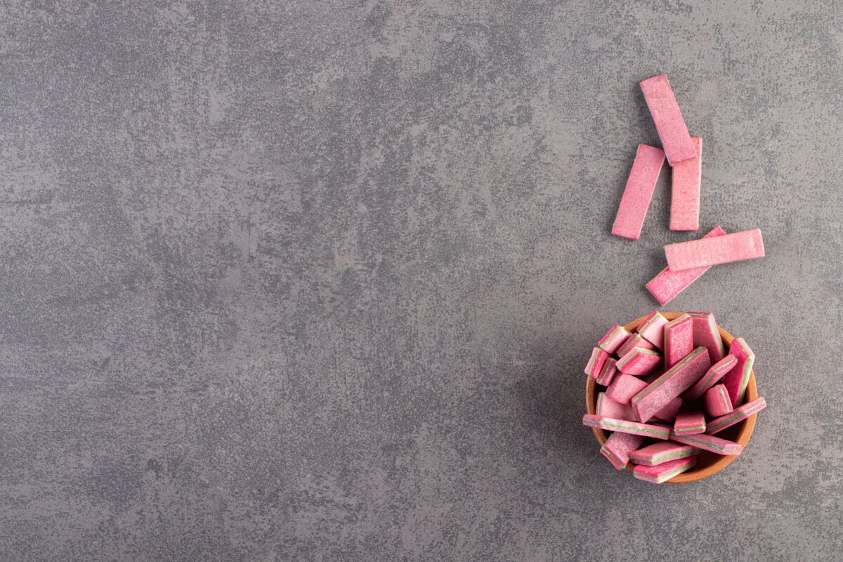 背景石桌上放着一碗长长的粉红色嚼棒糖零食五颜六色
