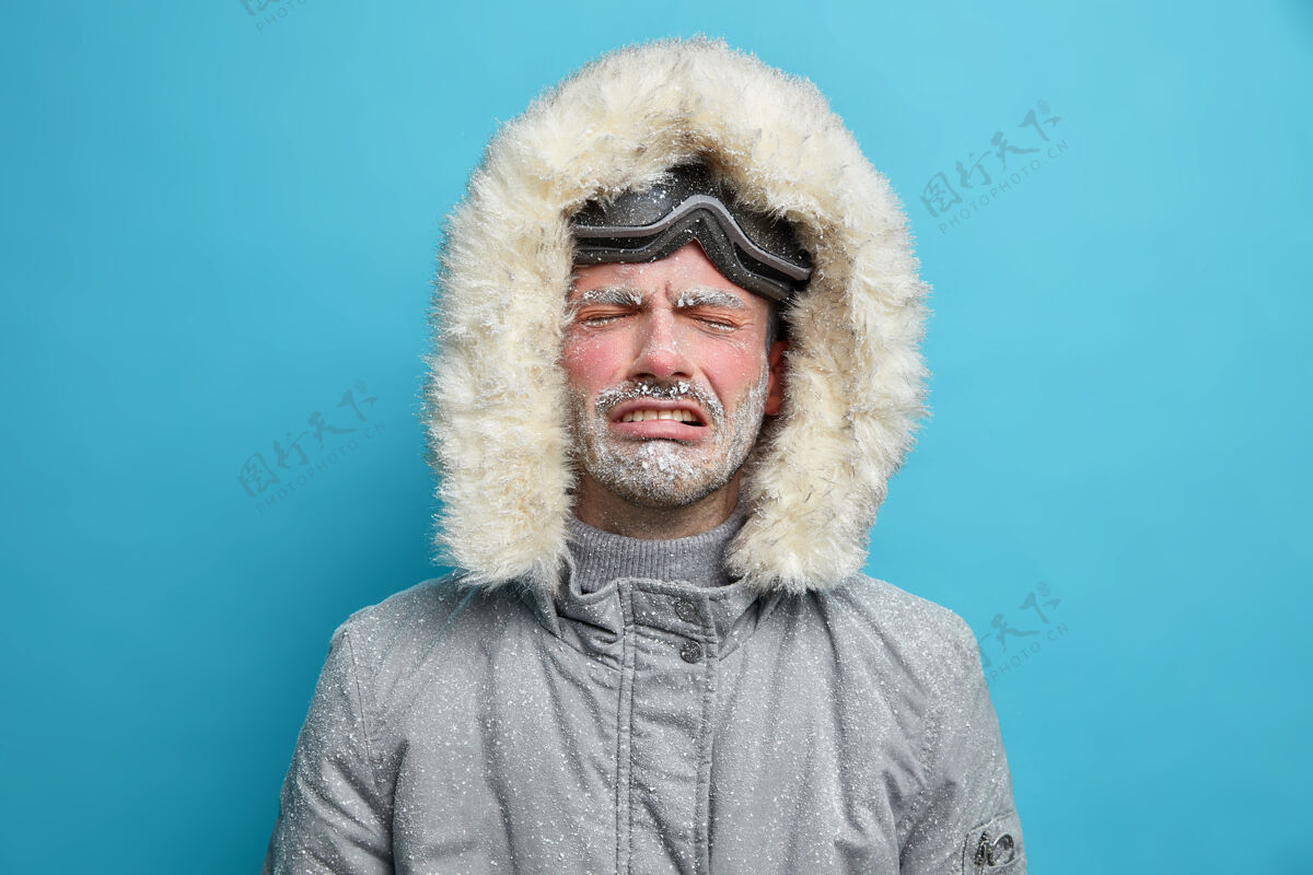沮丧在暴风雪和暴风雪中 一个绝望的心烦意乱的冻僵的男人穿着防热灰色夹克 戴着兜帽去滑雪不高兴哭泣男性