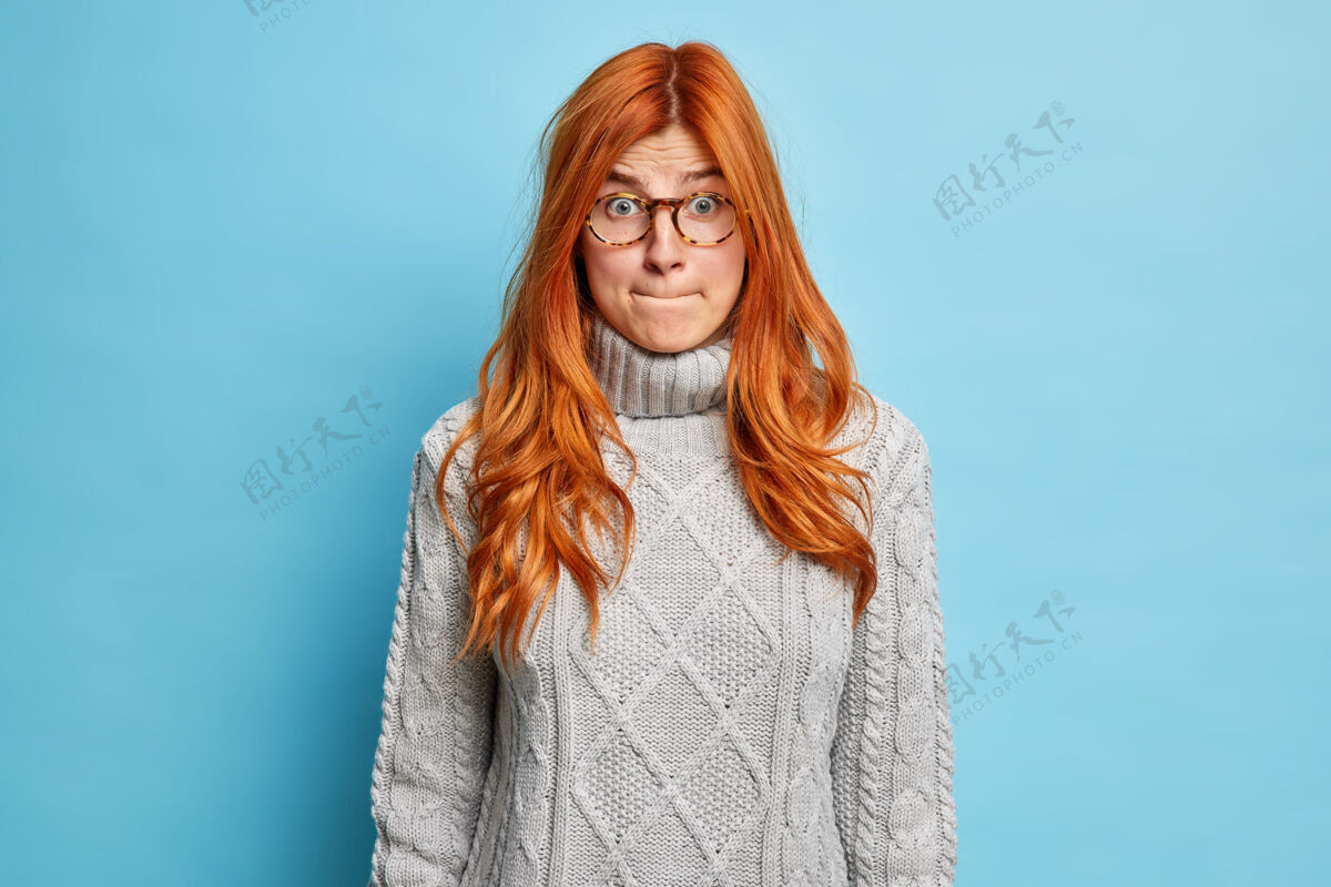 肖像不高兴不解的红发女青年压着嘴唇 神情尴尬 一脸震惊的表情 穿着毛衣和眼镜休闲面部负面