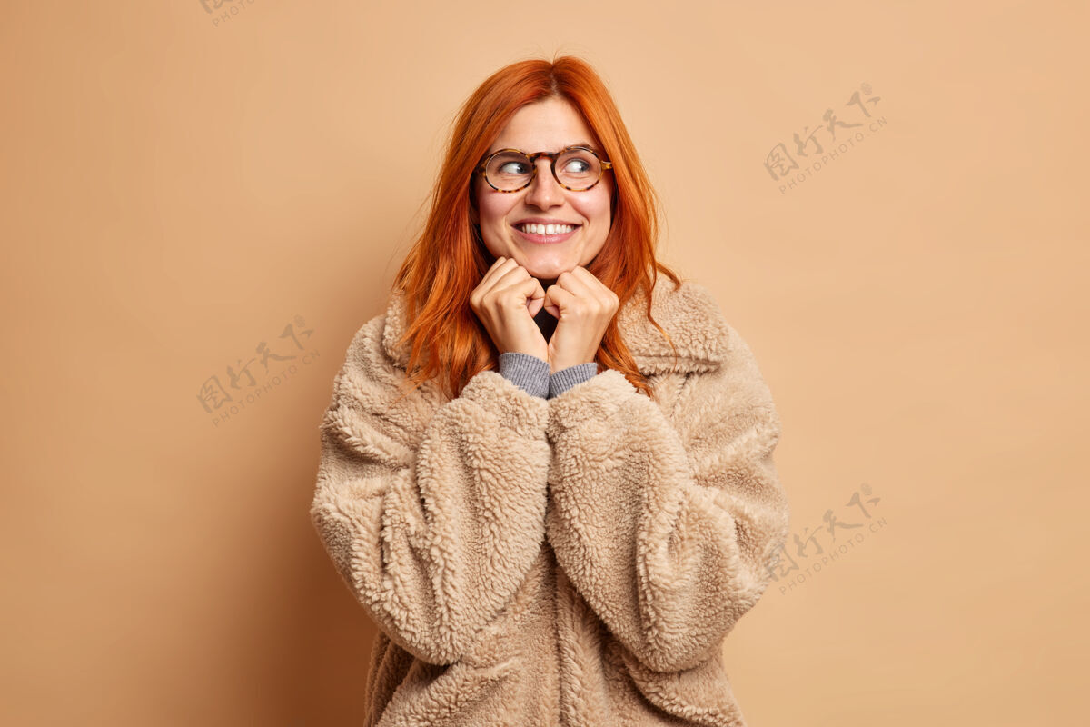 温暖漂亮红发女人的画像手放在下巴下快乐地看着别处 梦见一件棕色外套的东西女士下巴女人