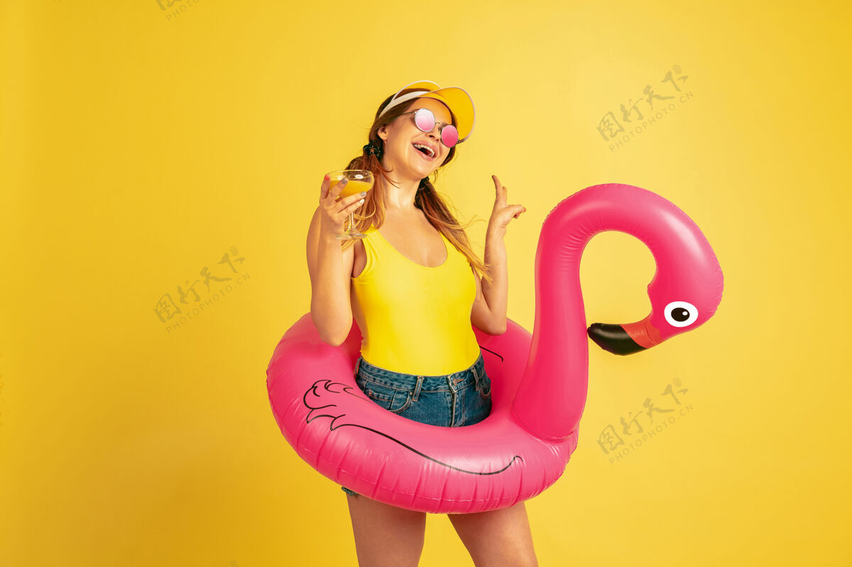 一半在沙滩上摆出鸡尾酒会的姿势黄色背景上的白种女人肖像戴帽子的漂亮女模特人类情感的概念 面部表情 销售 广告夏日 旅游 度假工作衬衫事业