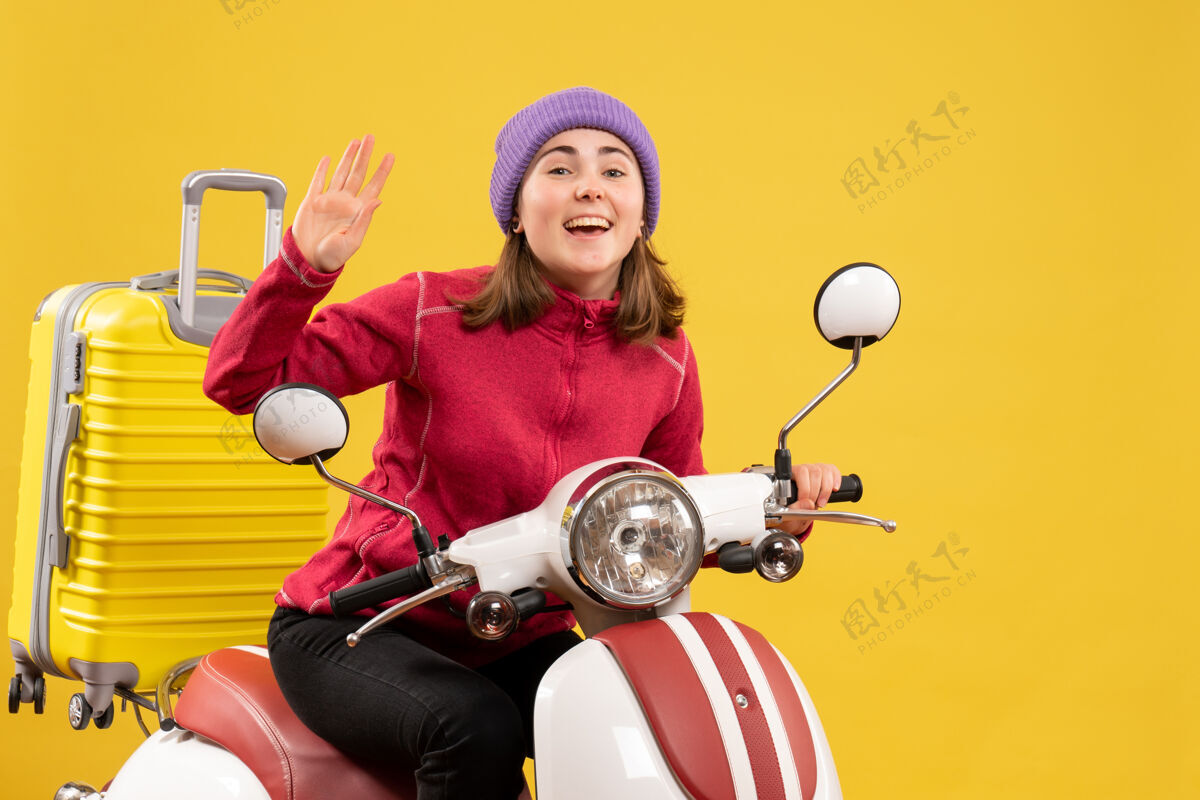 运动前方景色欢快的小女孩坐在轻便摩托车上挥舞着手快乐模型肖像