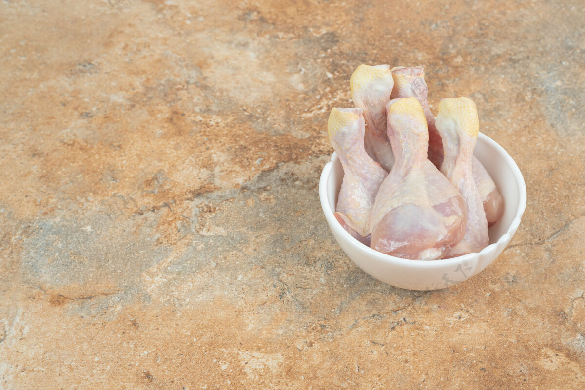 大理石未经料理的鸡腿放在大理石表面的白色盘子里生的配料美味