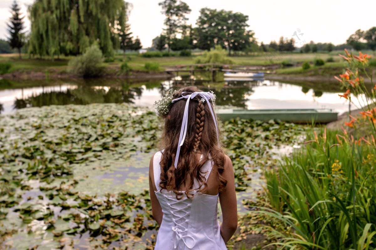 仪式美丽的女人站在美丽花园的池塘前花女士年轻