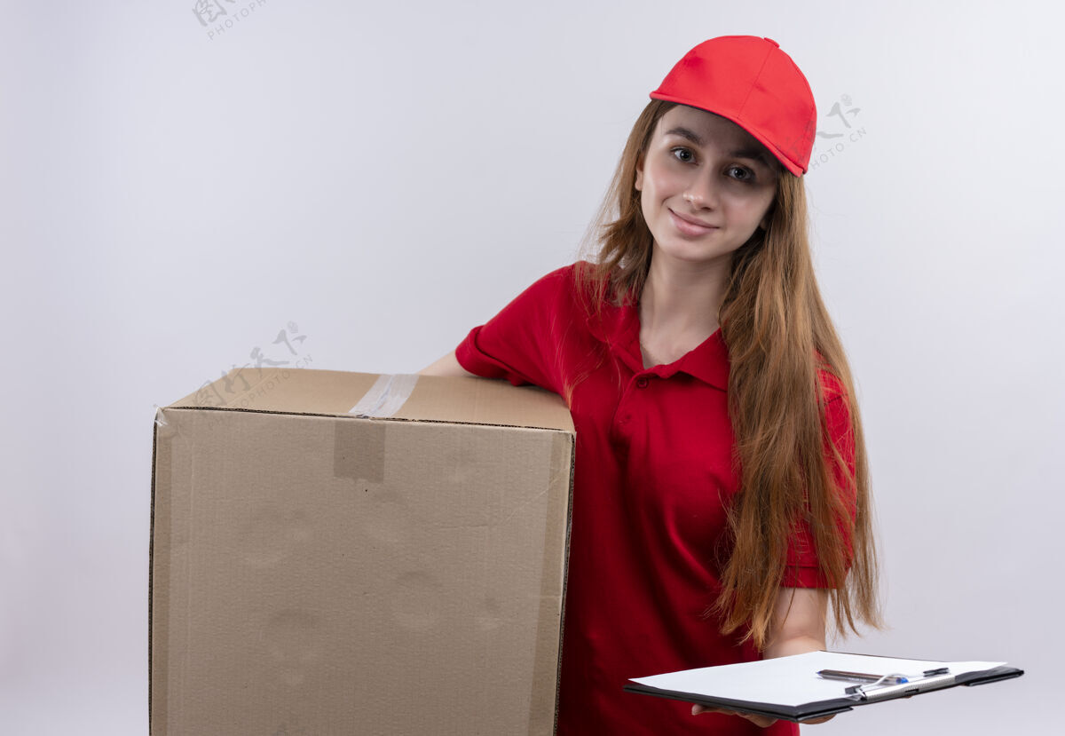 送货高兴的年轻送货女孩在红色制服举行的盒子和剪贴板上孤立的白色空间女孩剪贴板请拿着
