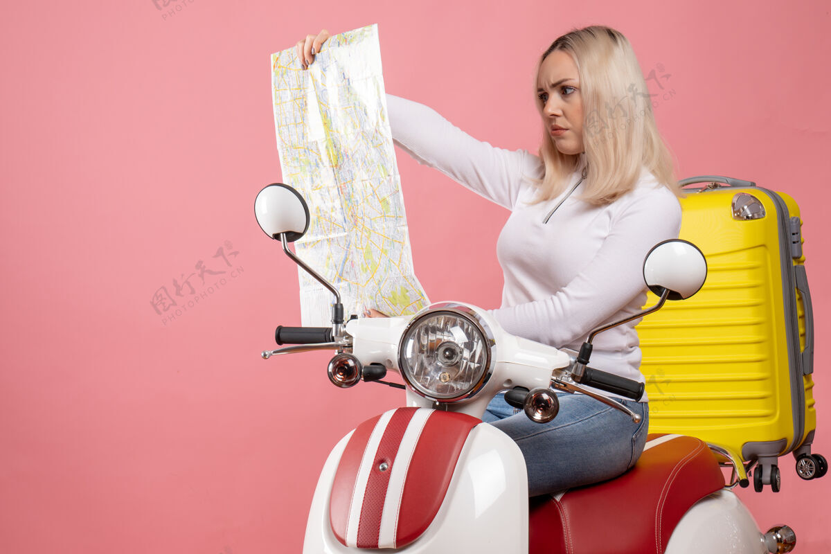 传送带前视图专注的金发女孩骑着轻便摩托车看地图前面数据磁盘