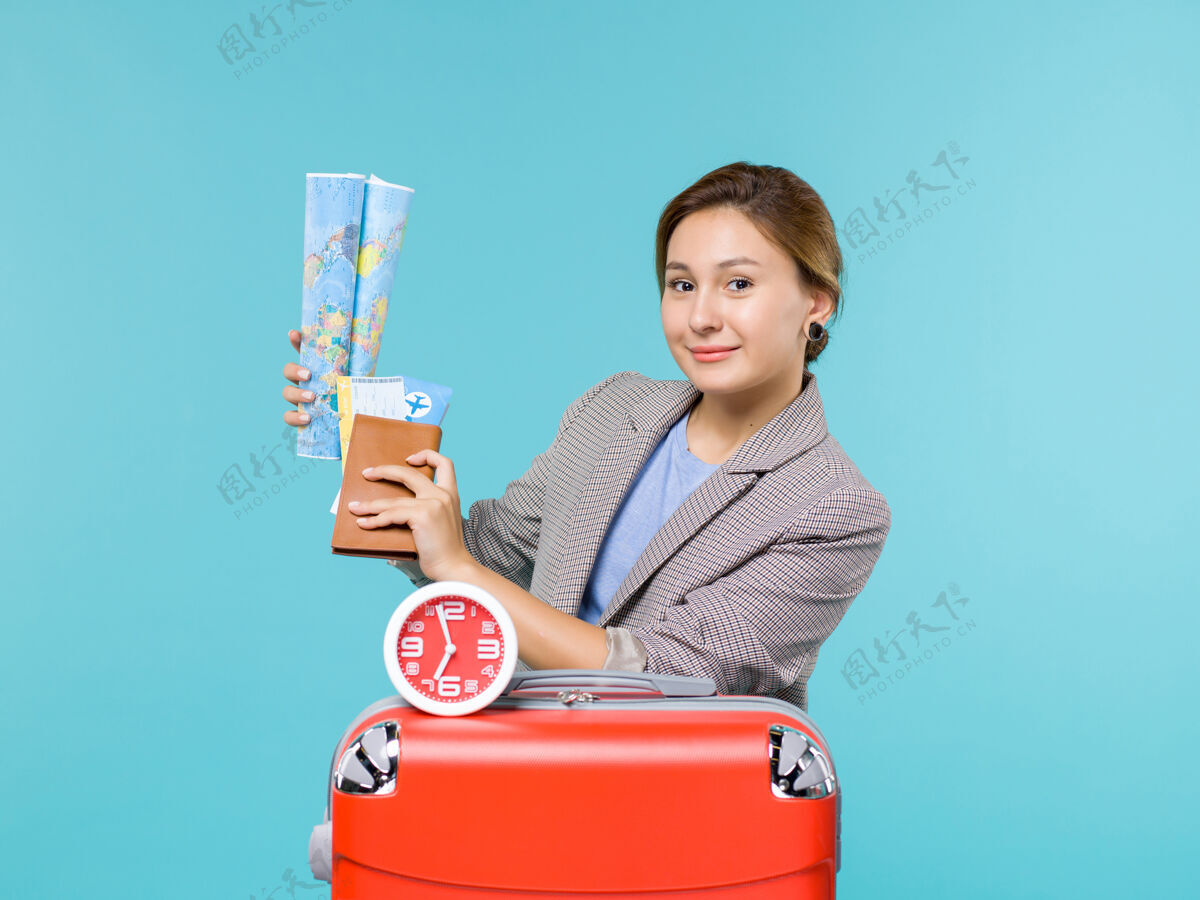 前面前视图中的度假女手持地图和机票上蓝色背景的飞机旅行地图女人微笑